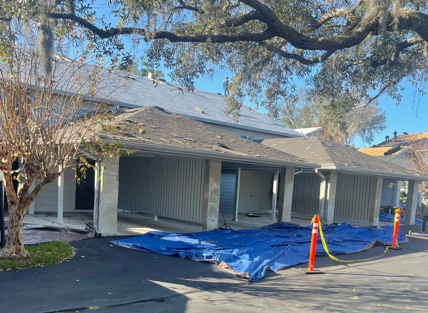 Multifamily Shingle Roof Replacement | Sentinel Roofing Belleview, FL Multifamily shingle roof tear-off and replacement with safety cones at a covered entryway by Sentinel Roofing in Belleview, FL