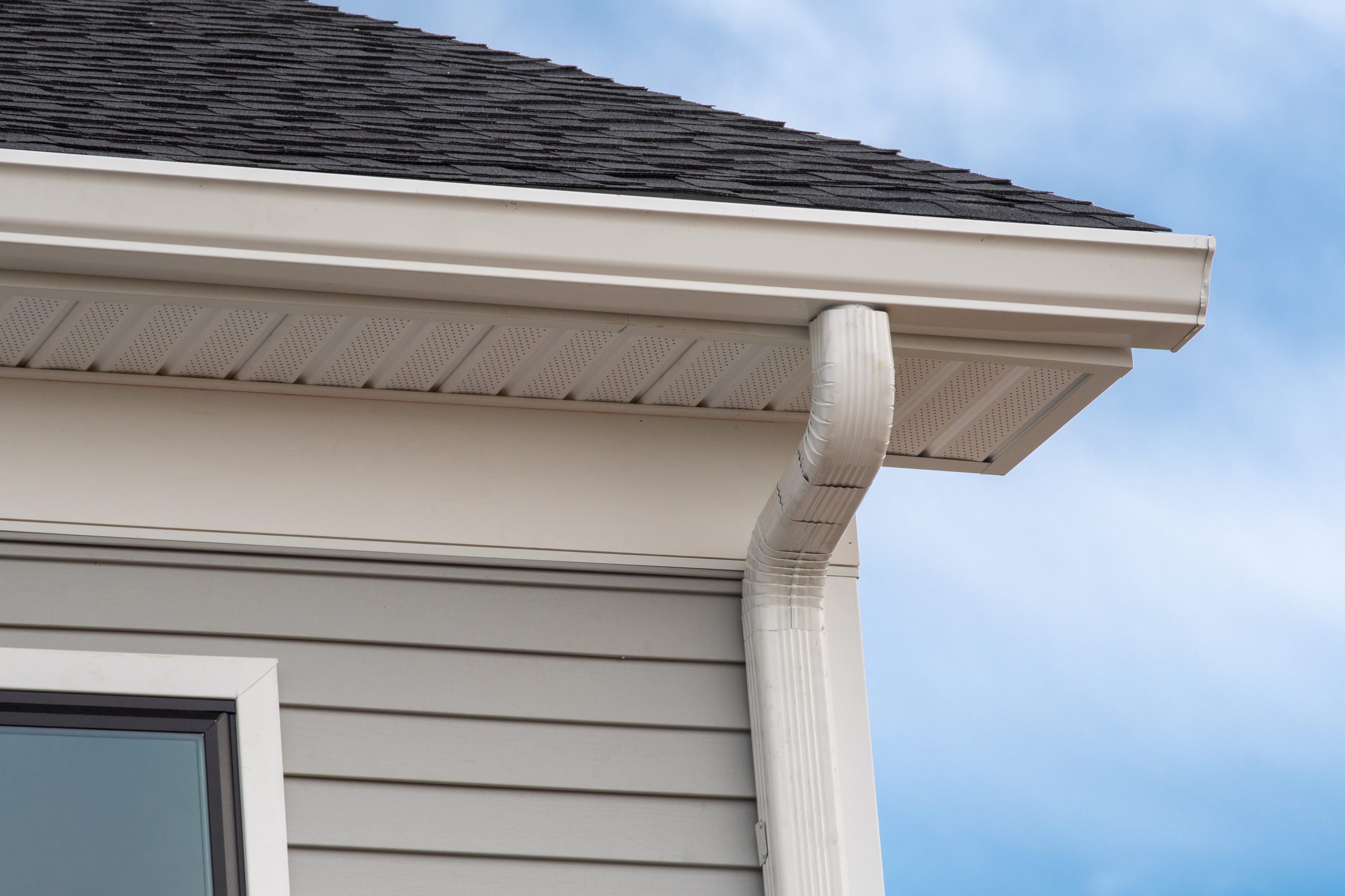 White seamless gutters on a home with gray siding and white trim.