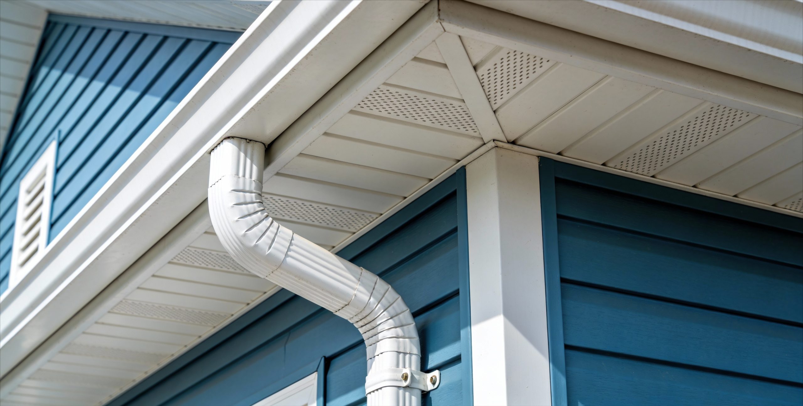 White seamless gutters on a home with vibrant blue siding.