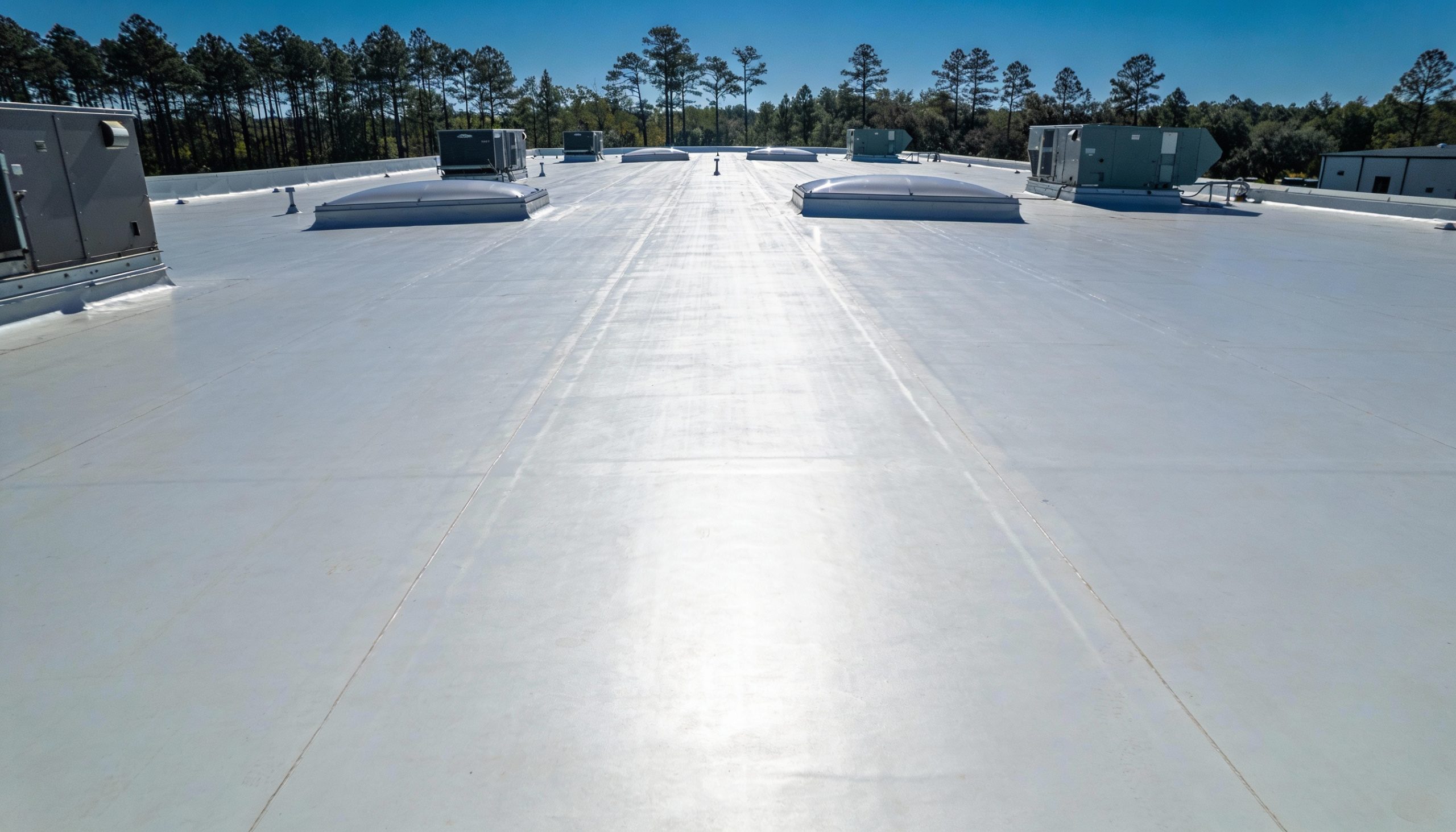 A TPO commercial rooftop with multiple skylights and HVAC units.