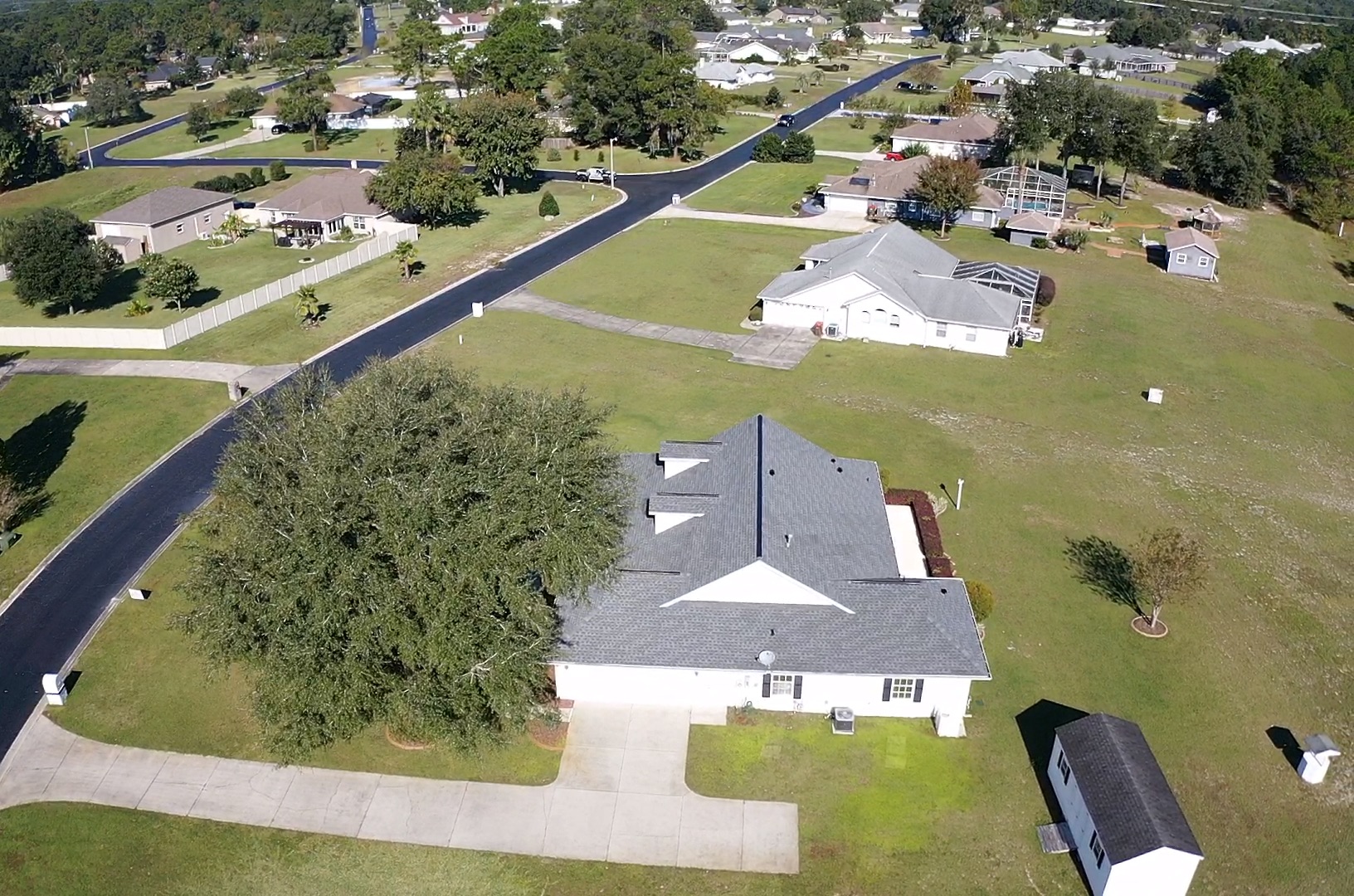 Drone view of a home with white siding, gray shingle roofing, and two dormers.