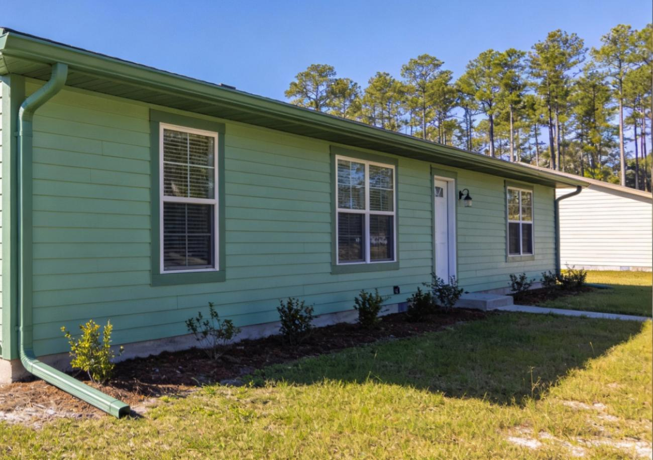 A home with light green siding, dark green trim and green seamless gutters.