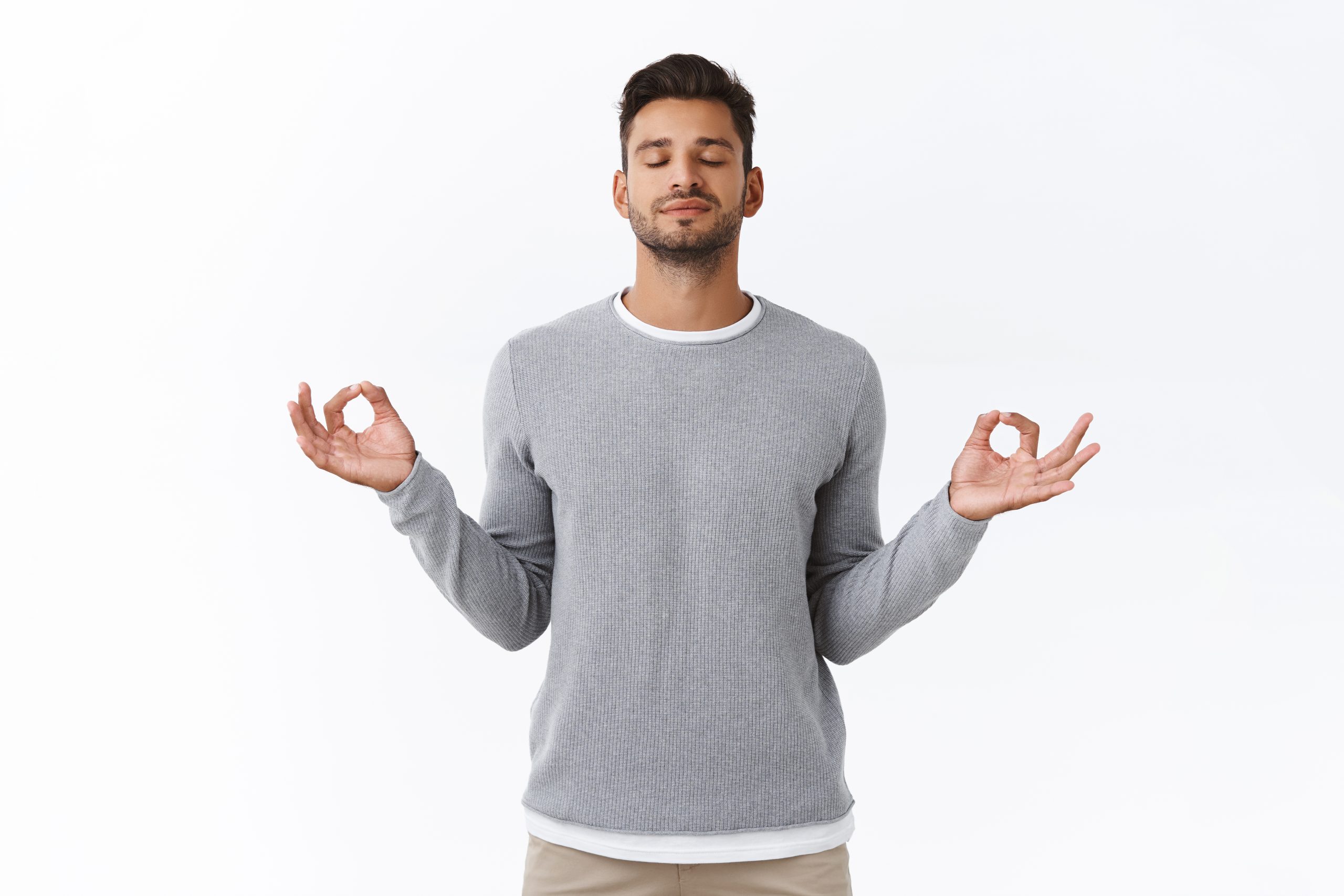 A man in front of a white background, holding his fingers together in a zen mindset.