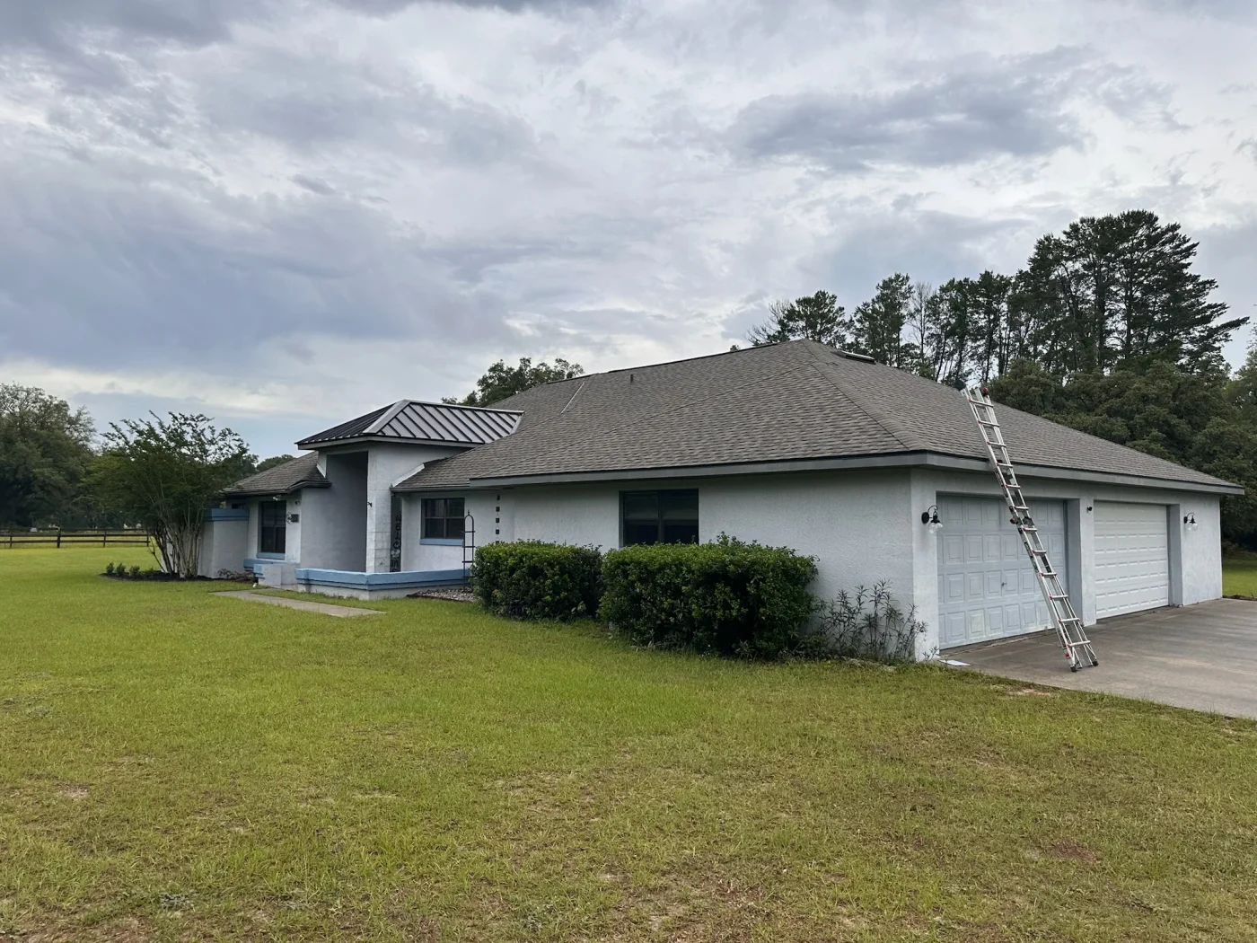 Locally Trusted Residential Roofing | Crystal River, FL | Sentinel Roofing A ladder leans against the side of a single-story home with a completed residential roofing project under an overcast sky.
