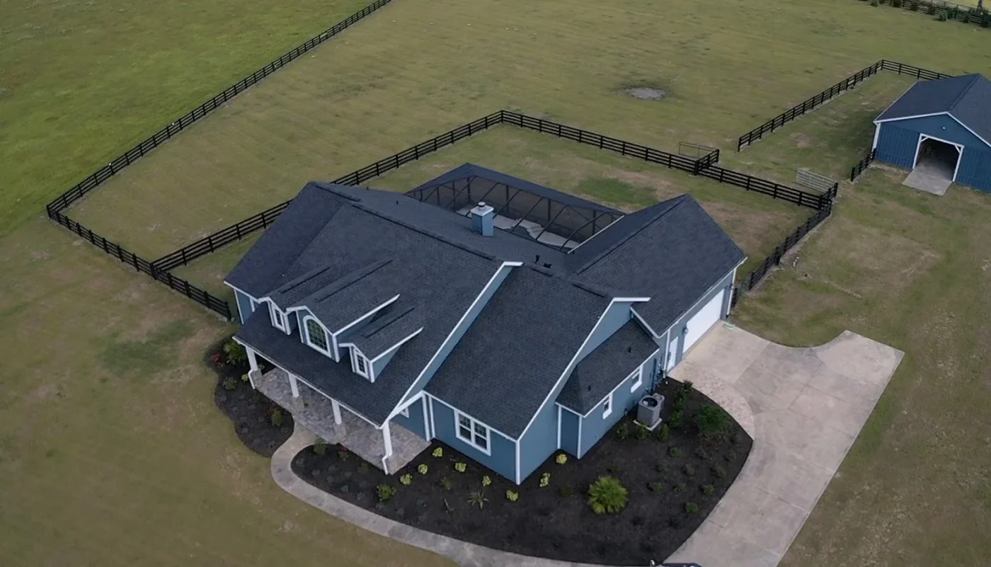 Superior Residential Roofing | Tavares, FL | Sentinel Roofing An aerial shot captures clean residential roofing on a blue house set within a spacious, fenced property.